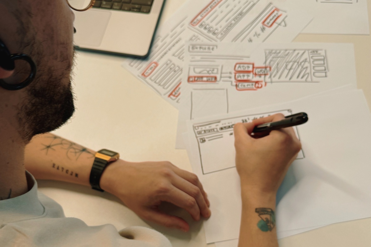 A man sketching a product interface wireframe with pen and paper.