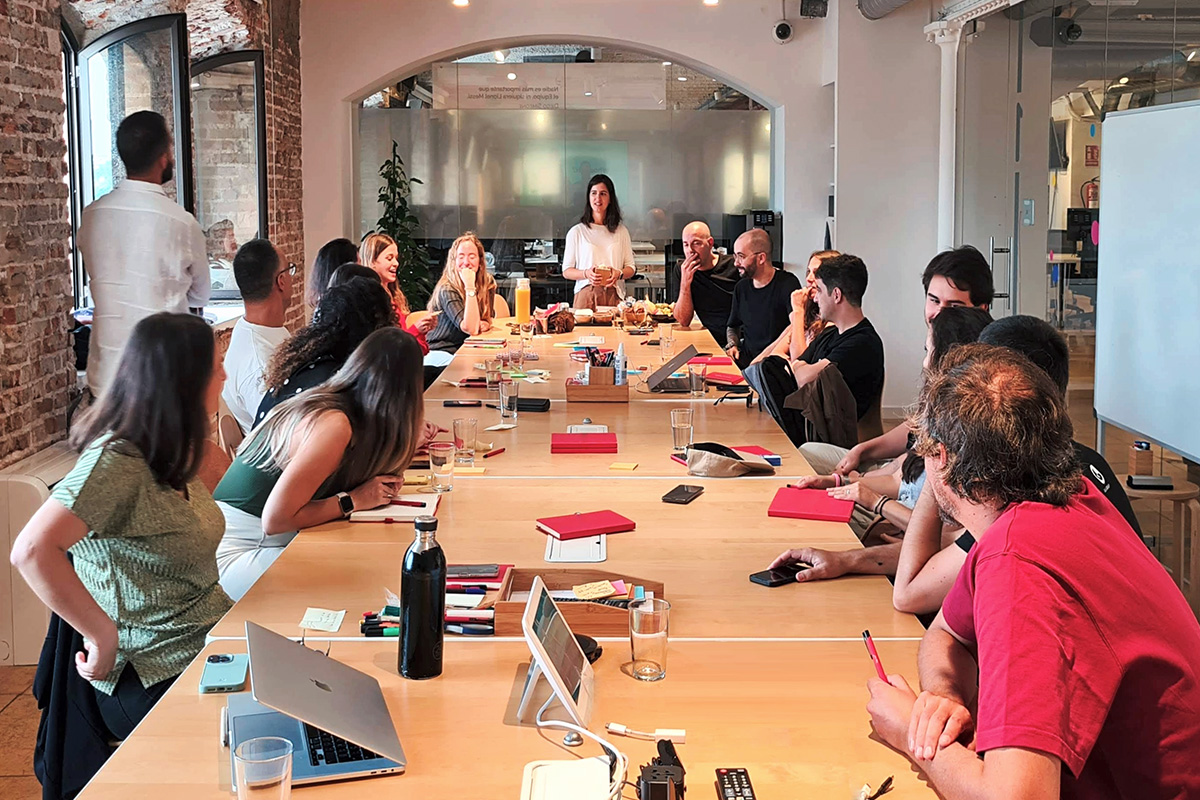 Long table with over 20 people sitting around it during a design worshop session.